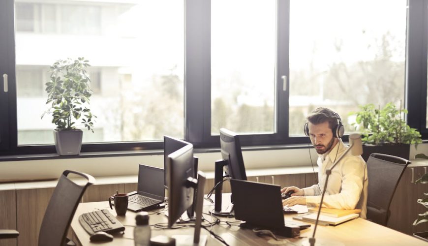 Man With Headphones Facing Computer Monitor